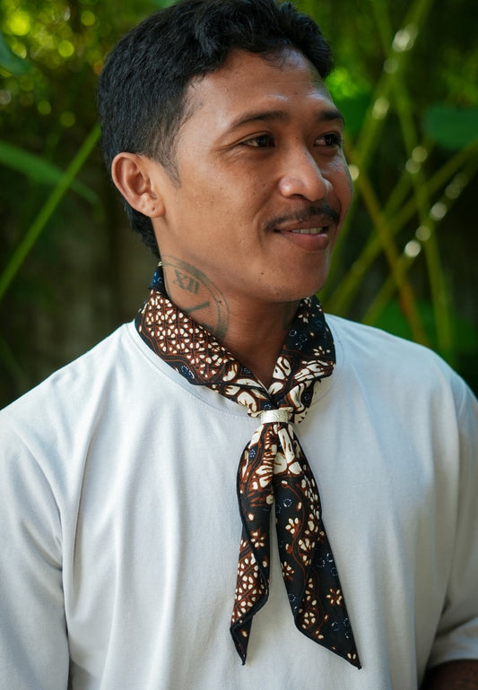 Man wearing a patterned scarf around his neck with a natural with batik sekar jagad