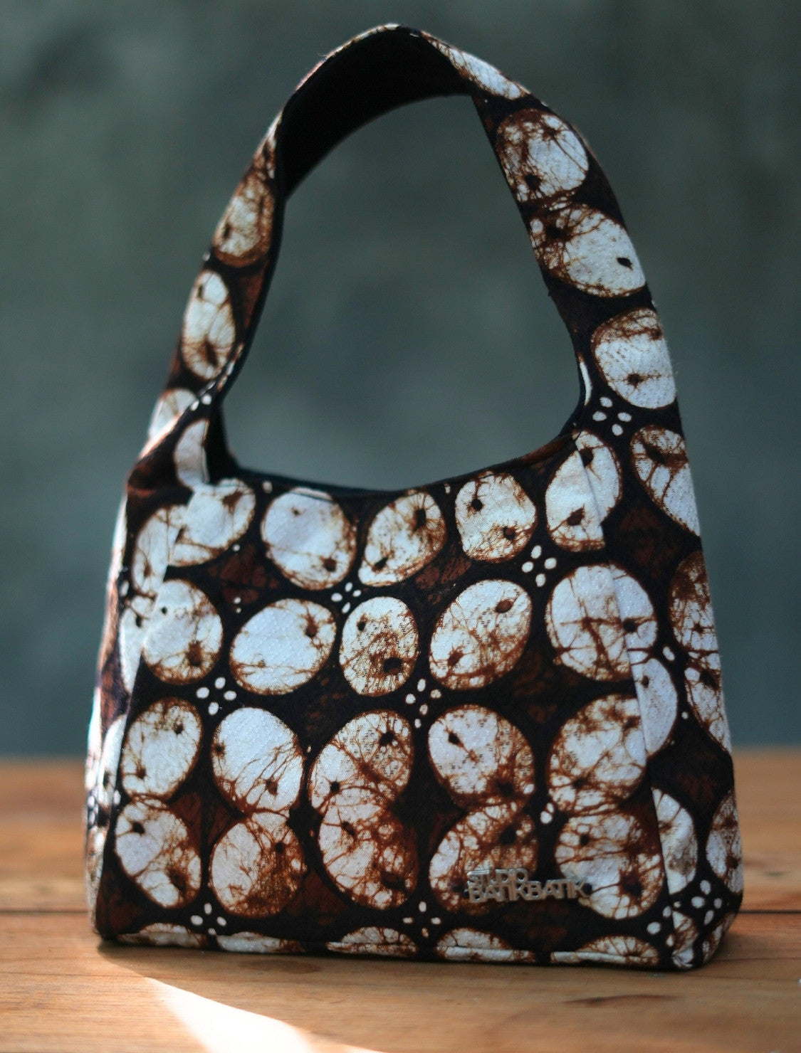 Handbag with a brown and white pattern on a wooden surface with Kawung Batik Pattern