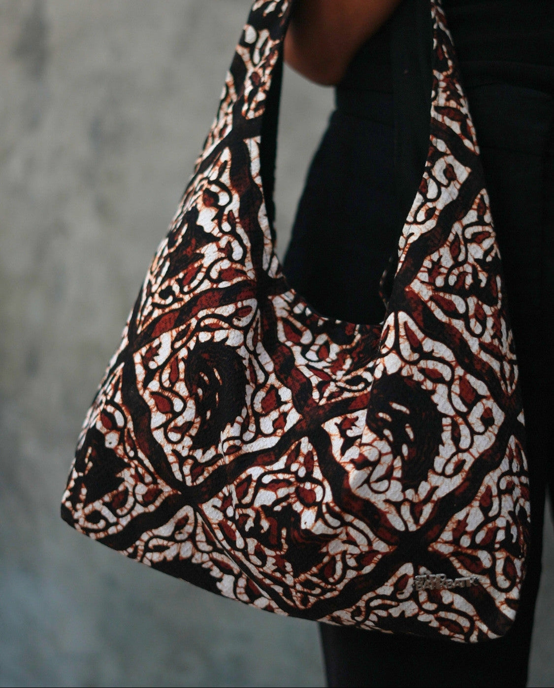 Patterned Batik bag held by a person against a neutral background