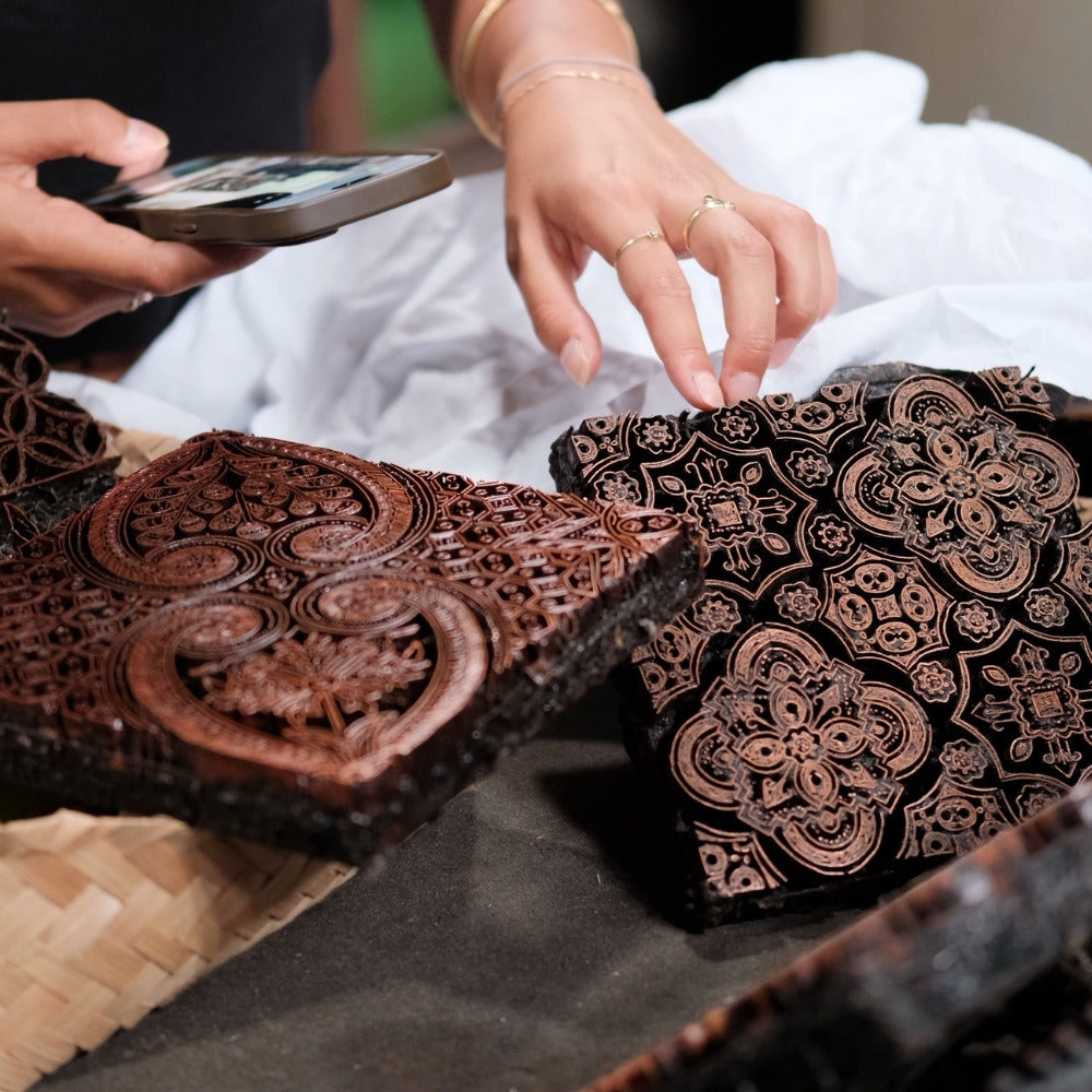 Batik artisan using hot wax and metal stamp to make Batik cap fabric