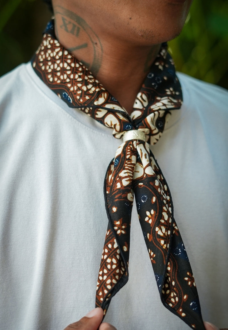 Person wearing a patterned scarf with a blurred background with a batik sekar jagad bandana