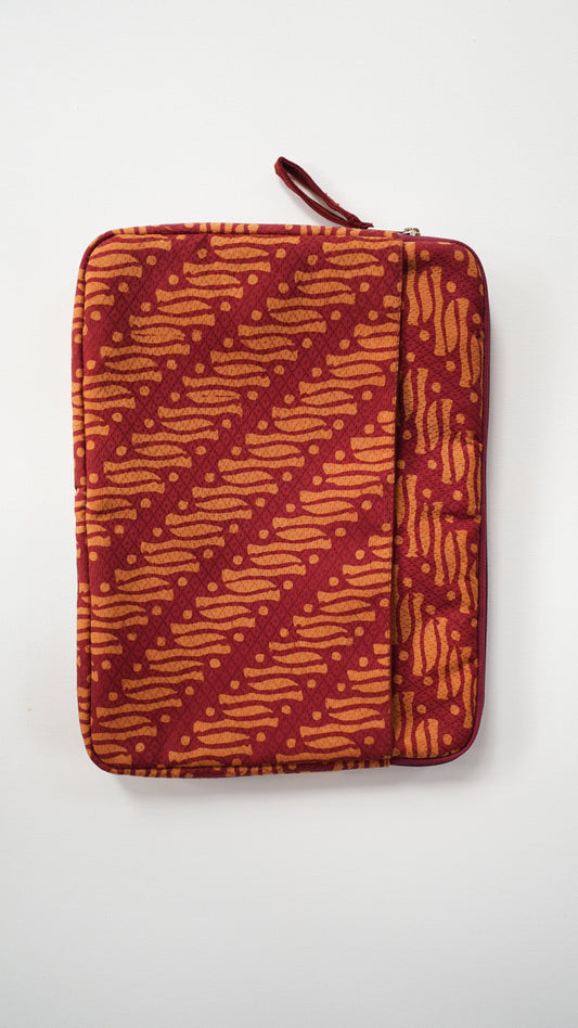 A zippered batik laptop sleeve or pouch with a red and orange batik-style pattern, shown flat against a plain white background.