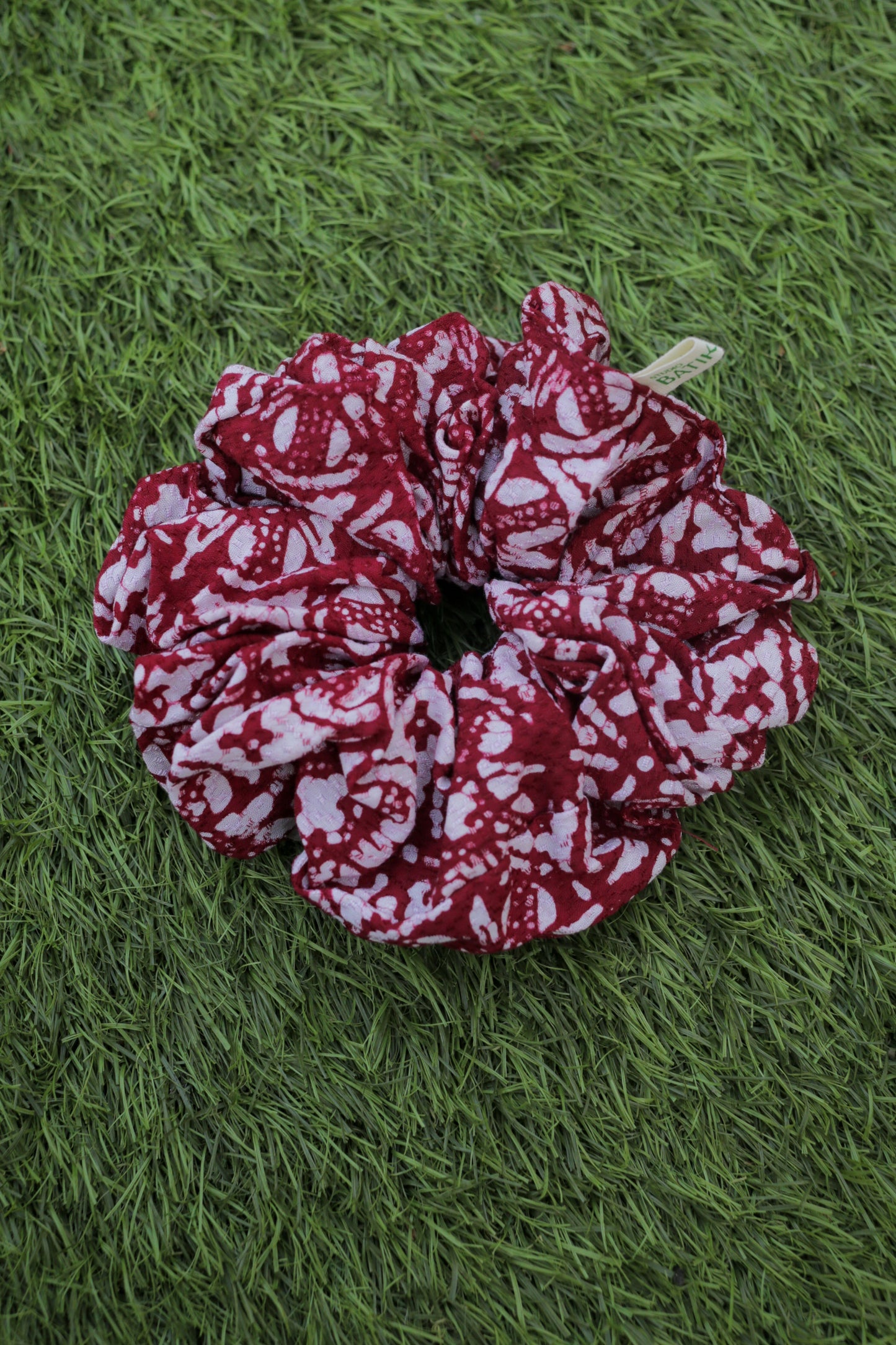 Red and white patterned batik  scrunchie on green grass