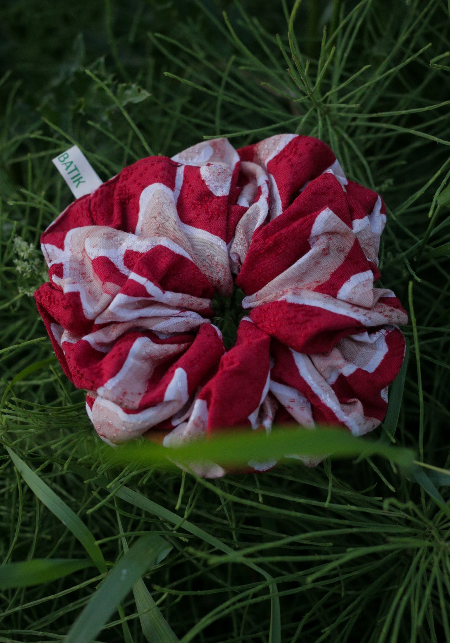 Red and white scrunchie on green grass